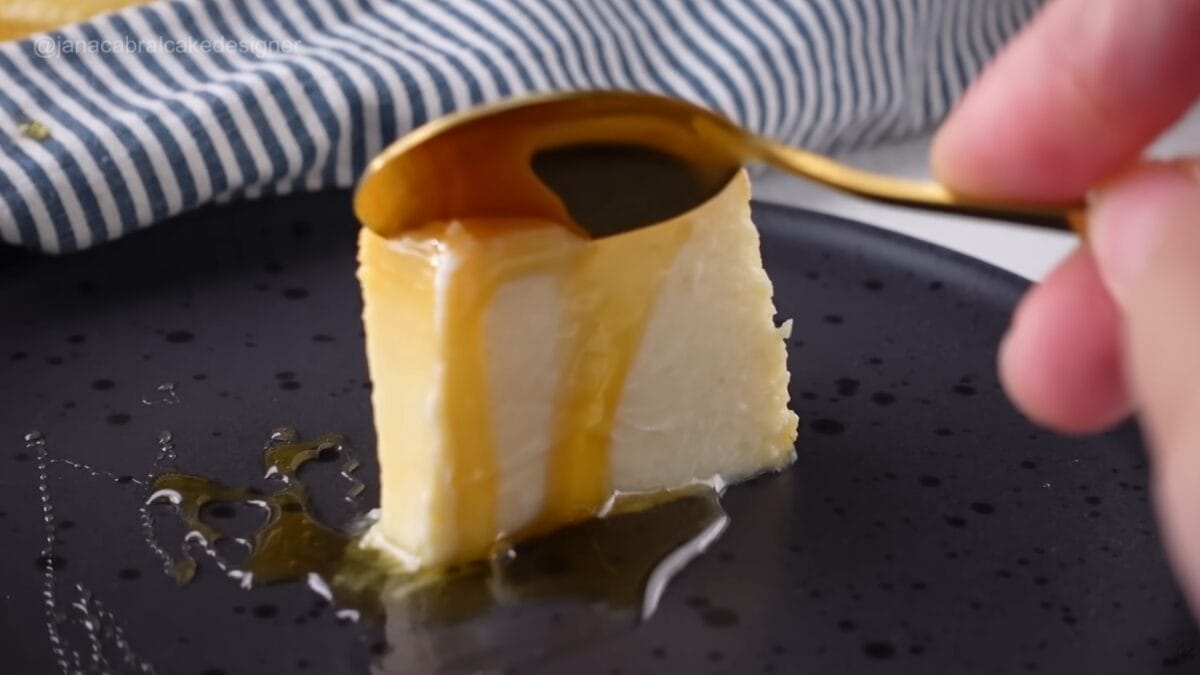 Pudim de iogurte inteiro com calda brilhante sendo despejada no centro da sobremesa