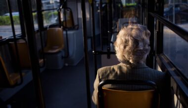 O femeie batrana merge cu autobuzul.