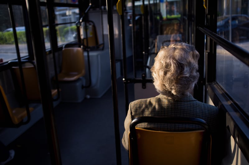 O femeie batrana merge cu autobuzul.