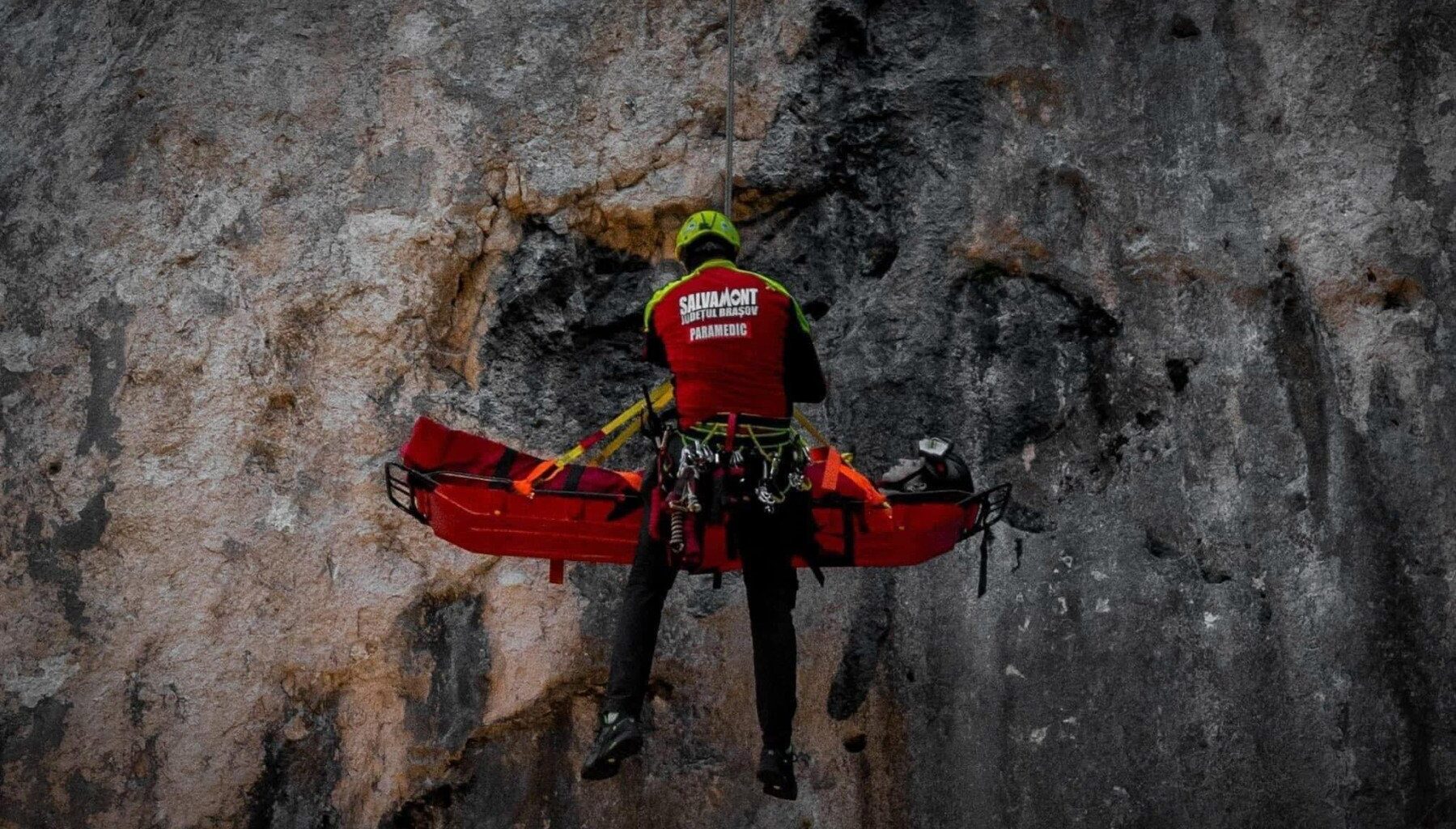 Un salvamontist coboara in coardă pe o stânca un turist ranit