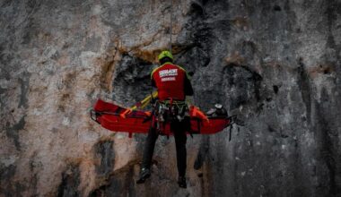 Un salvamontist coboara in coardă pe o stânca un turist ranit