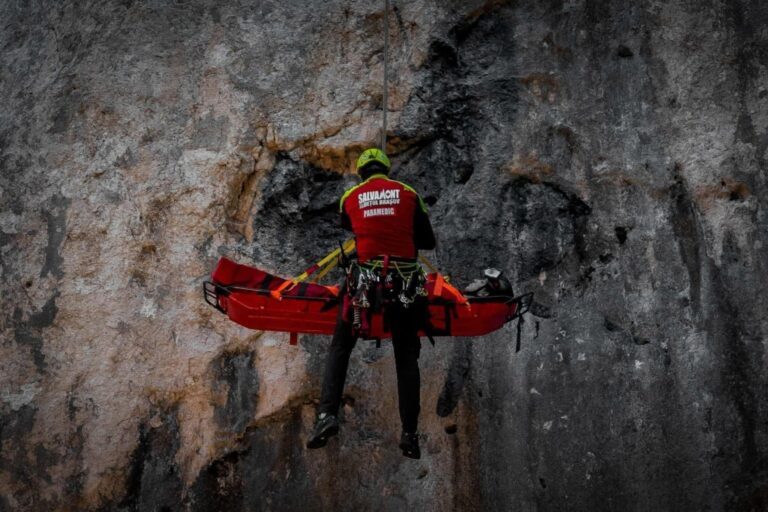 Un salvamontist coboara in coardă pe o stânca un turist ranit