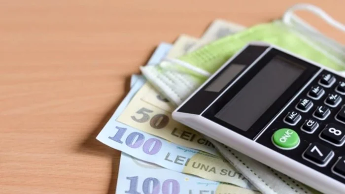 Un calculator pus pe mai multe bancnote de 50 și 100 de lei