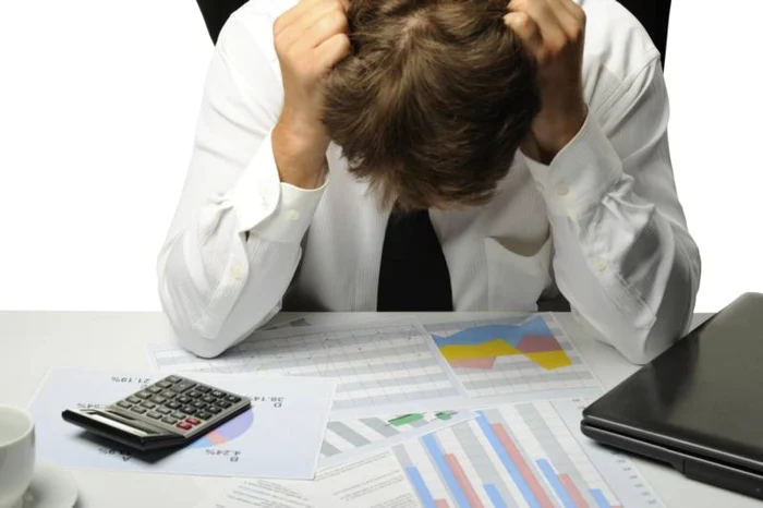 Un antreprenor își ține capul în mâini îngrijorat de cifrele afacerii sale