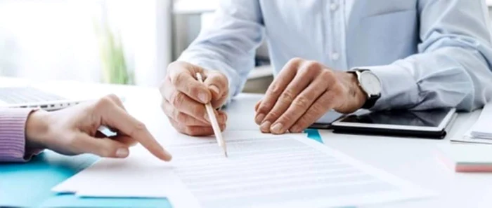 Un avocat arată petentului unde trebuie să semneze cererea e chemare în judecată a autorităților