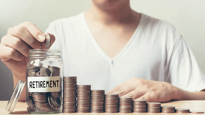 Cineva așează monede în fișicuri, puse în ordine crescătoare, până la un borcan cu monede