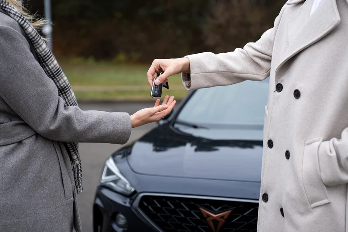 Vechiul proprietar predă cheile mașinii cumpărătorului