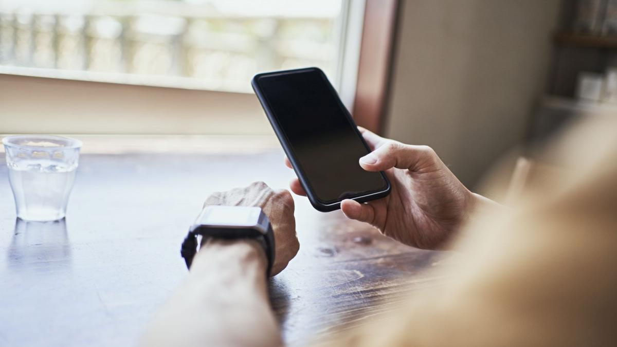 barbat cu telefonul in mana si smarwatch la cealalta mana