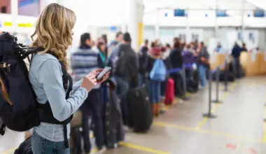 femeie care se uita pe telefon in aeroport