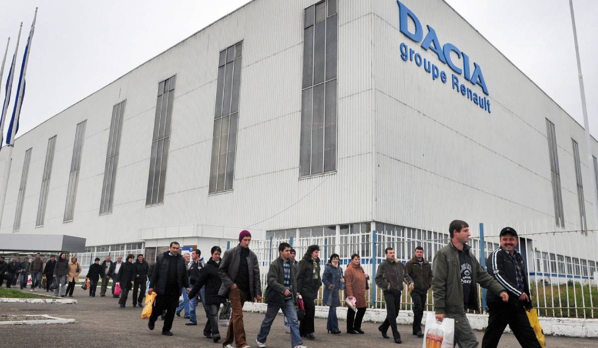 Fotografie cadru larg cu uzina Dacia Mioveni, exterior, iarna, mai multi muncitori, in haine groase, in mers