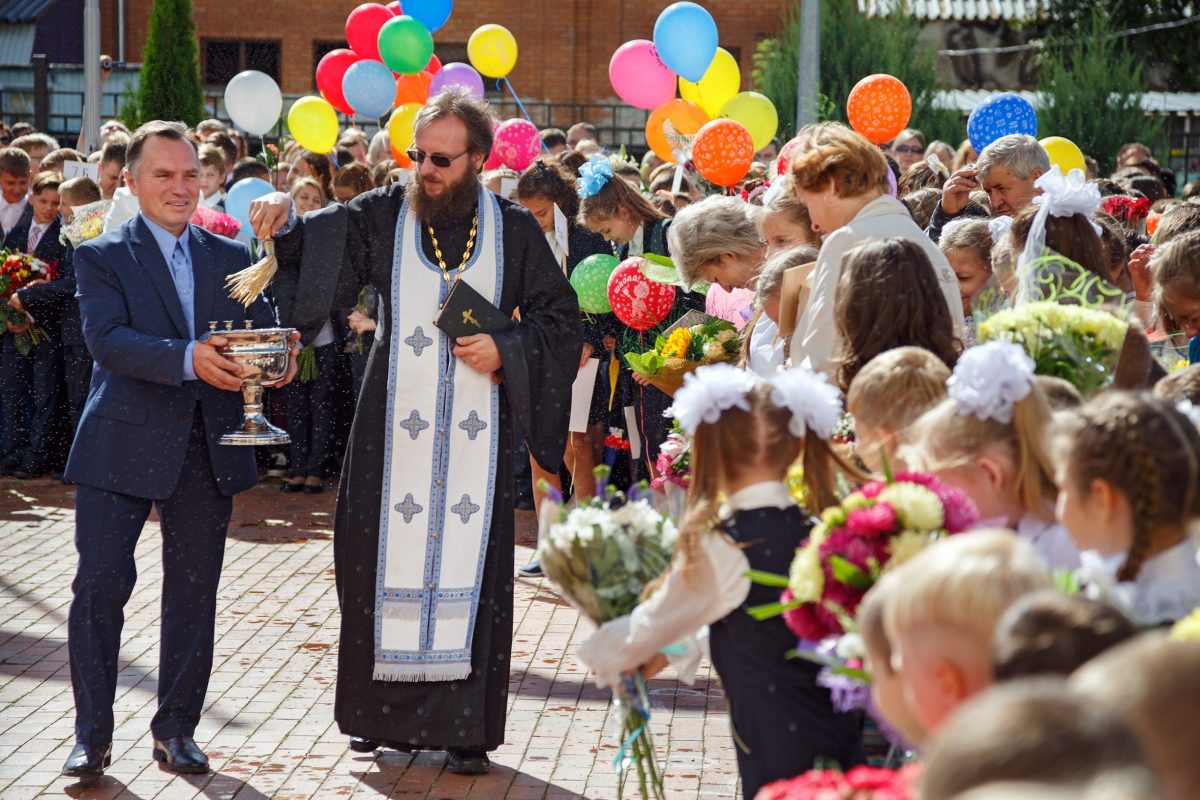 Preot ortodox care sfinteste curtea scolii la inceput de an scolar