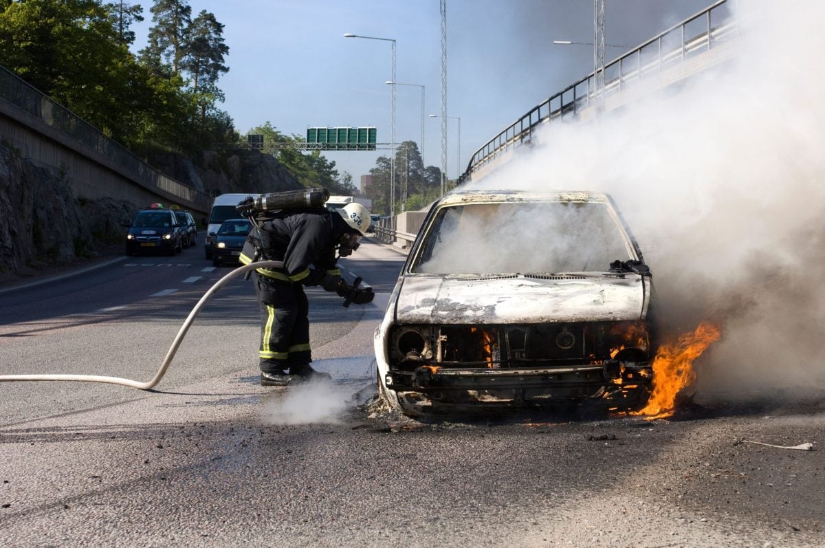 Un pompier stinge focul pornit în urma unui accident de mașină pe autostradă.