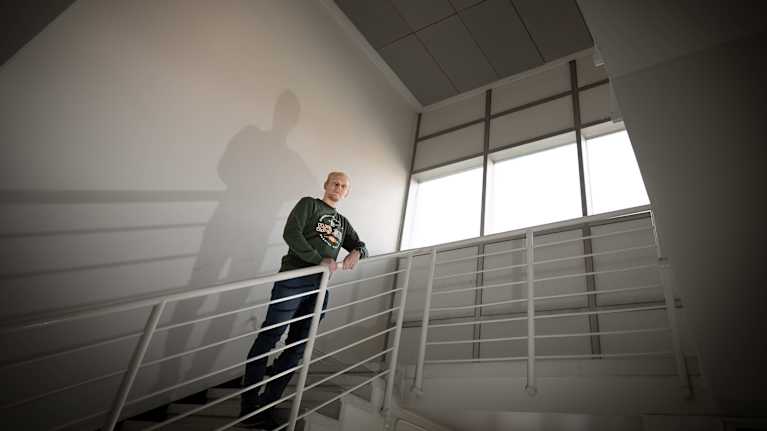 Peter Söderström står i en trappa och tittar ner mot kameran. Bakom honom syns hans skugga mot väggen.