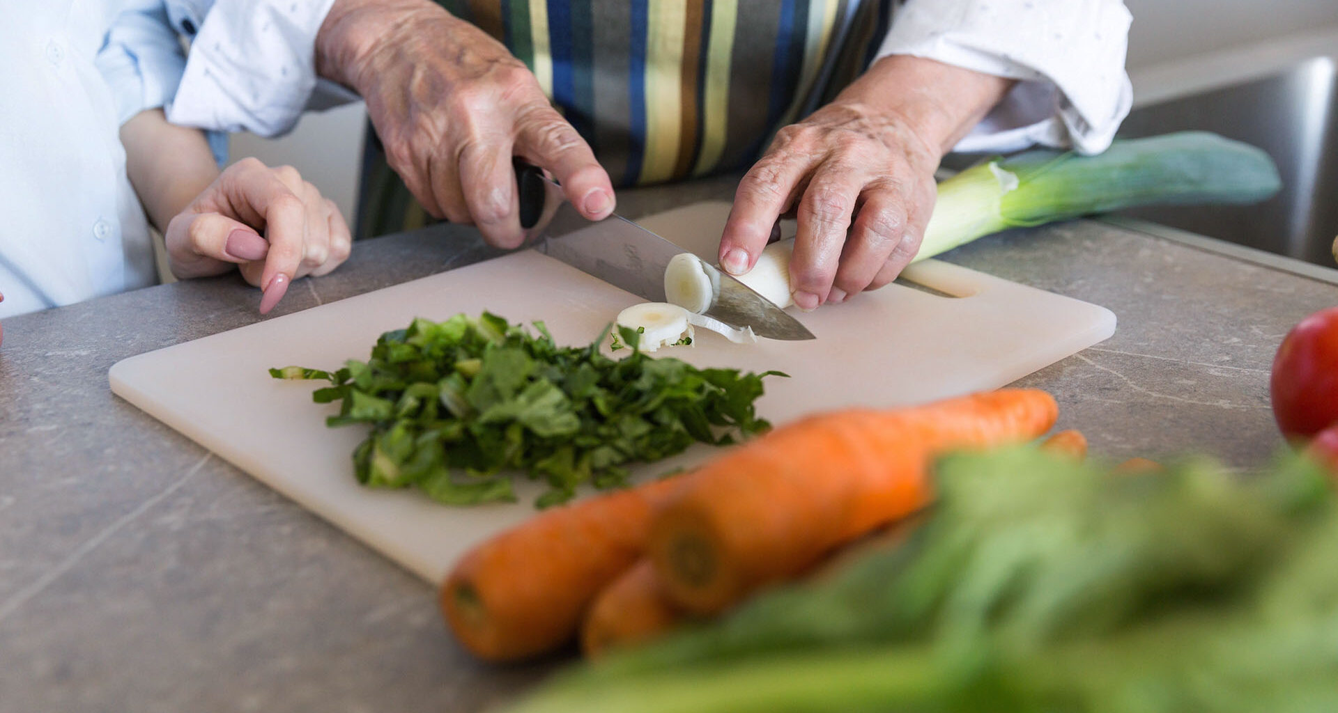Äldre par lagar mat och skär upp grönsaker.