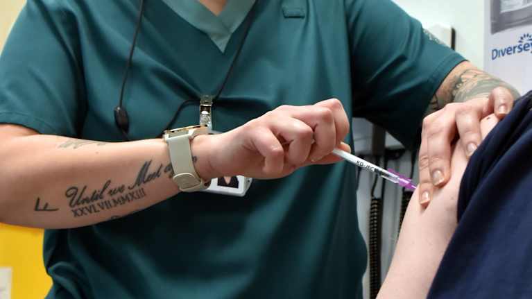 En sjukvårdare vaccinerar en patient i armen.