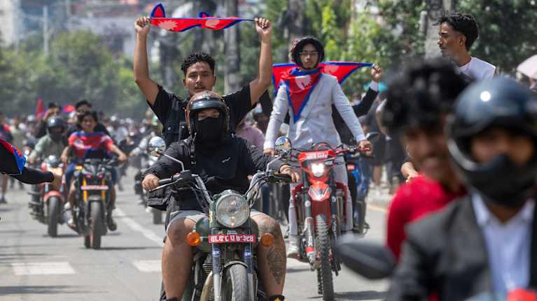 Personer på motorcyklar i Nepal med nepalesiska flaggor.