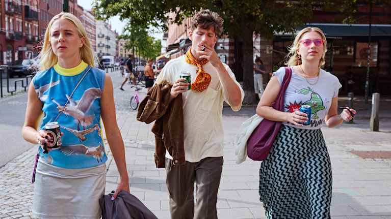 Tre unga människor som går på gatan i Malmö, det är sommar.