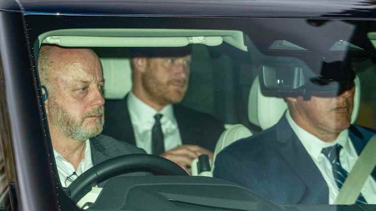 En suddig bild av prins Harry i baksätet av en bil med säkerhetsvakt och chaufför i framsätet.