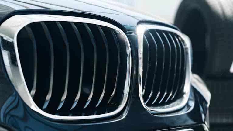 Närbild av en svart BMWs karakteristiska njurformade grill, med däck i bakgrunden.