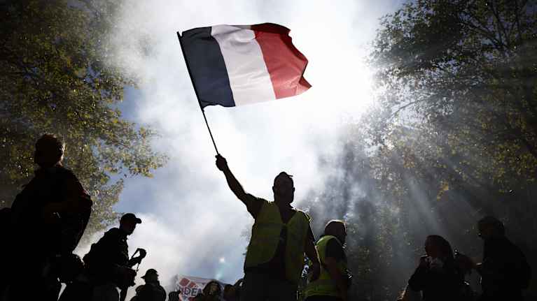 En demonstrant viftar med den franska flaggan i Paris.