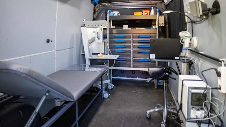 Mobil sjukvårdsenhet utrustad med säng, medicinsk utrustning och arbetsstation för vårdpersonal.