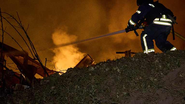 En brandman i Ukraina försöker släcka en eldsvåda efter bombardemang.