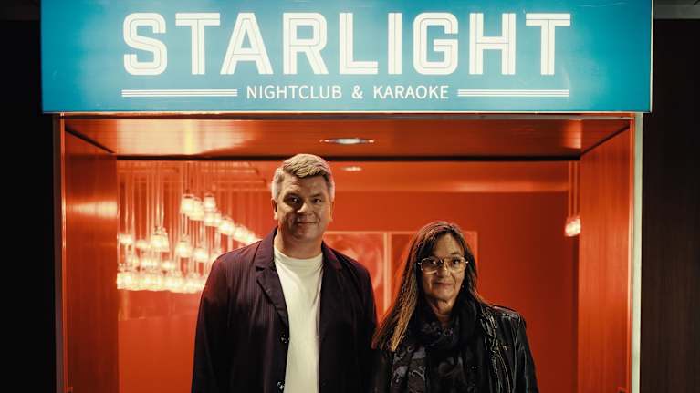 Mats Strandberg och Malin Lagerlöf ser rakt in i kameran och ler, bakom den syns en upplyst skylt där det står Starlight nattklubb.