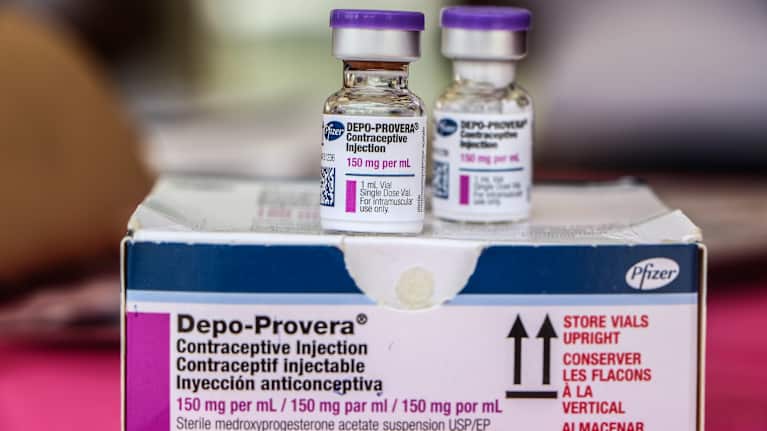 Två små flaskor med injektionsvätska står på en pappask. På asken och flaskorna står det Depo-Provera Contraceptive Injection intill tillverkaren Pfizers logotyp.