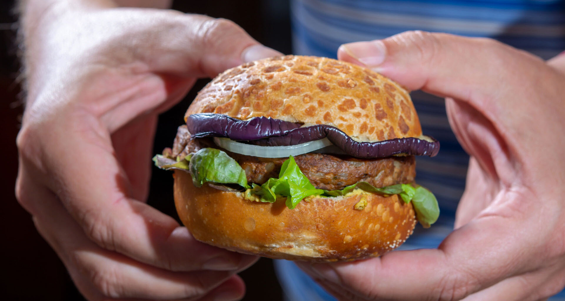 Man håller i en växtbaserad hamburgare.