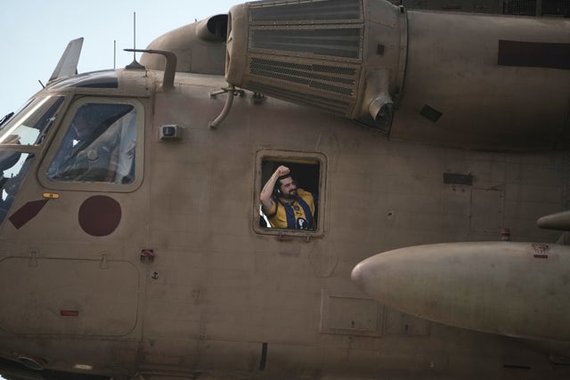 En person som hållits gisslan gestikulerar ur fönstret på en helikopter.  