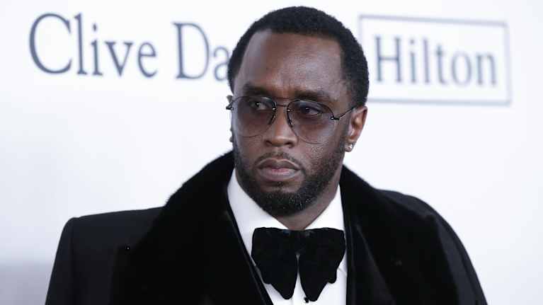 Sean "Diddy" Combs i kostym och fluga tittar åt sidan. Han har glasögon på sig.