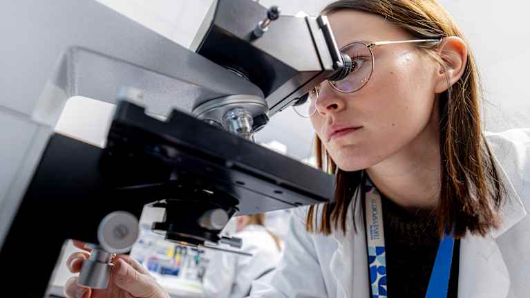 En forskare arbetar med ett mikroskop i ett laboratorium. 