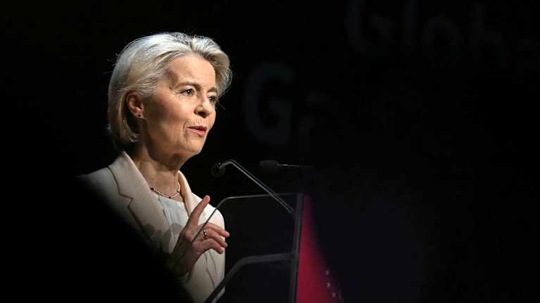 Ursula von der Leyen i en talarstol, med ett höjt pekfinger. 