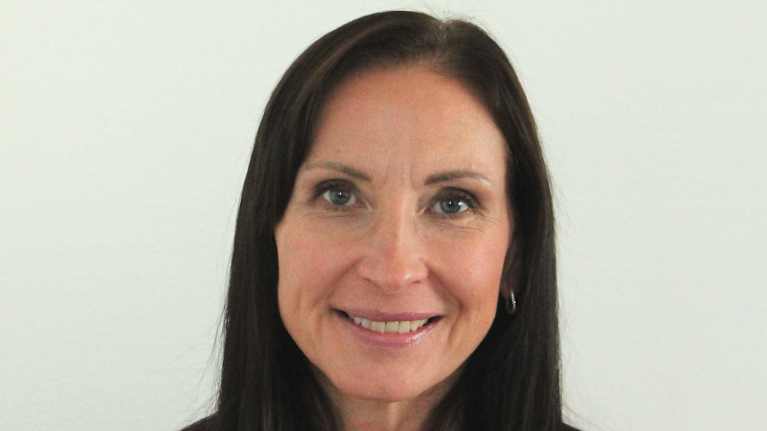 Kvinna med långt, mörkt hår, klädd i en flerfärgad tröja.