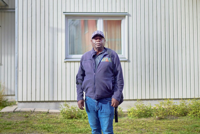 Andre Mbuta, 55, från Kongo-Kinshasa har bott i modulhus i fem år: ”Det är bra, men mycket dyrt. Om du har ett jobb går det bra men det är svårt som arbetslös. Alla pengar går till hyra, mat och räkningar”.