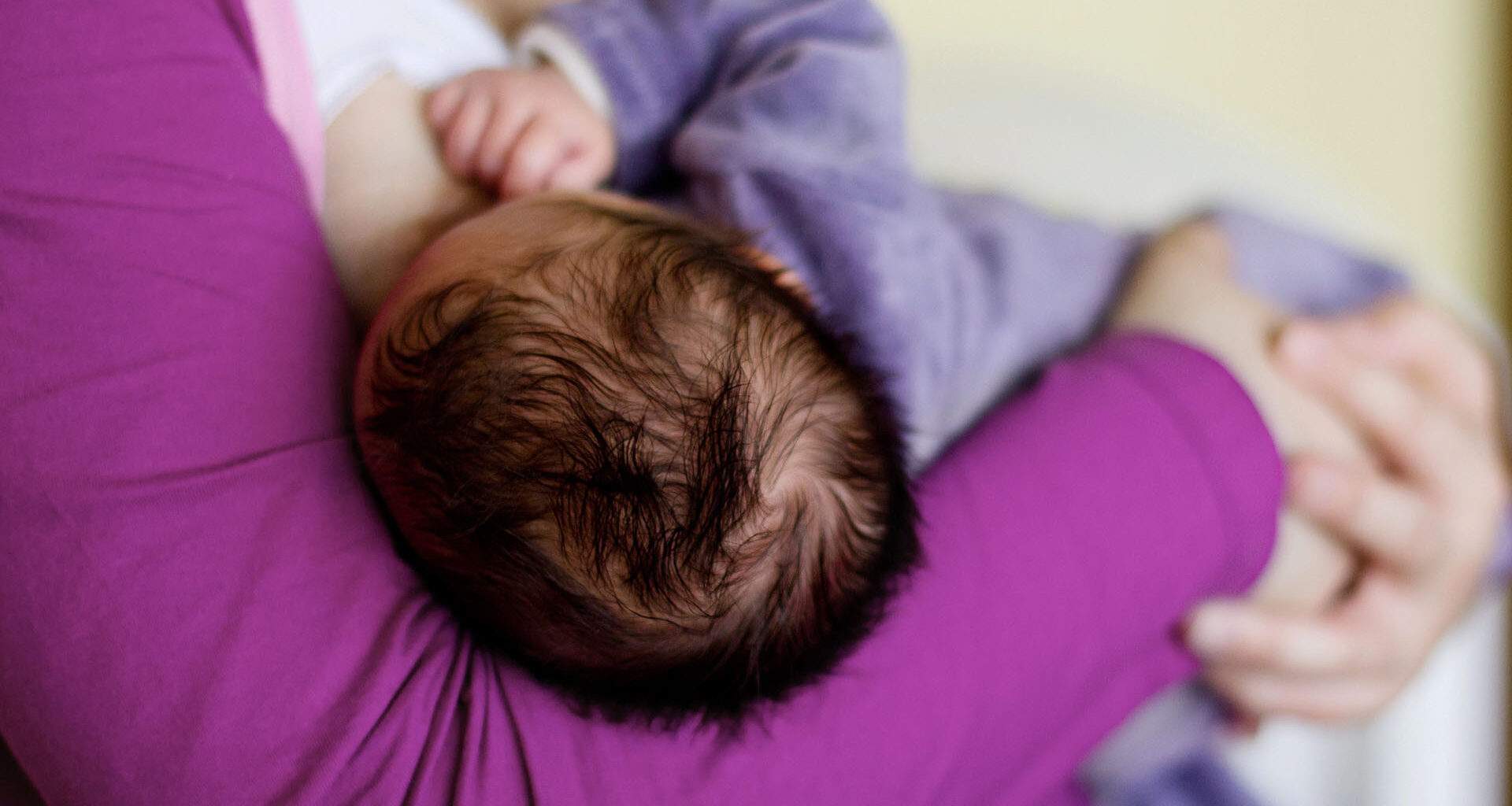 Bebis med mörkt hår ammas.