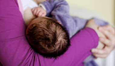 Bebis med mörkt hår ammas.