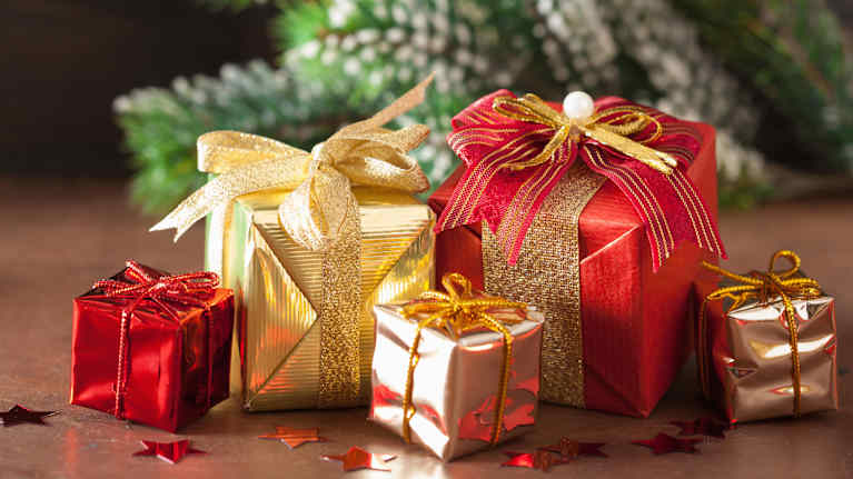 Julklappar inslagna i glittrande papper med eleganta rosetter.