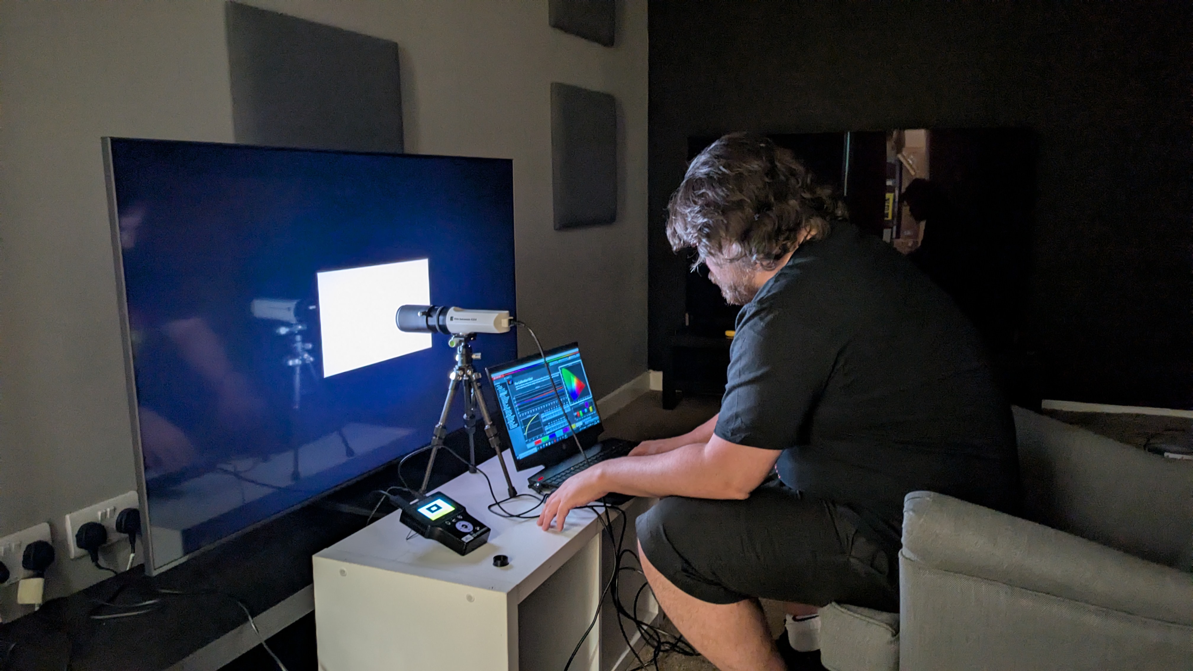 Samsung QN80F testas med kalibreringsutrustning av en person.