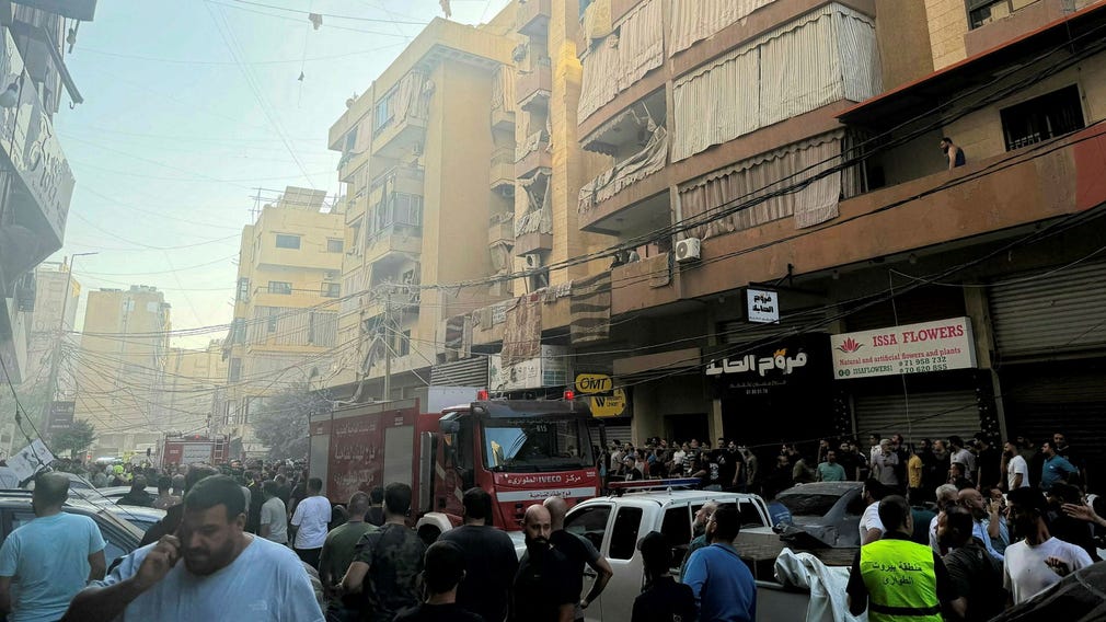 Människor samlas på gatan vid huset som attackerats av Israel.