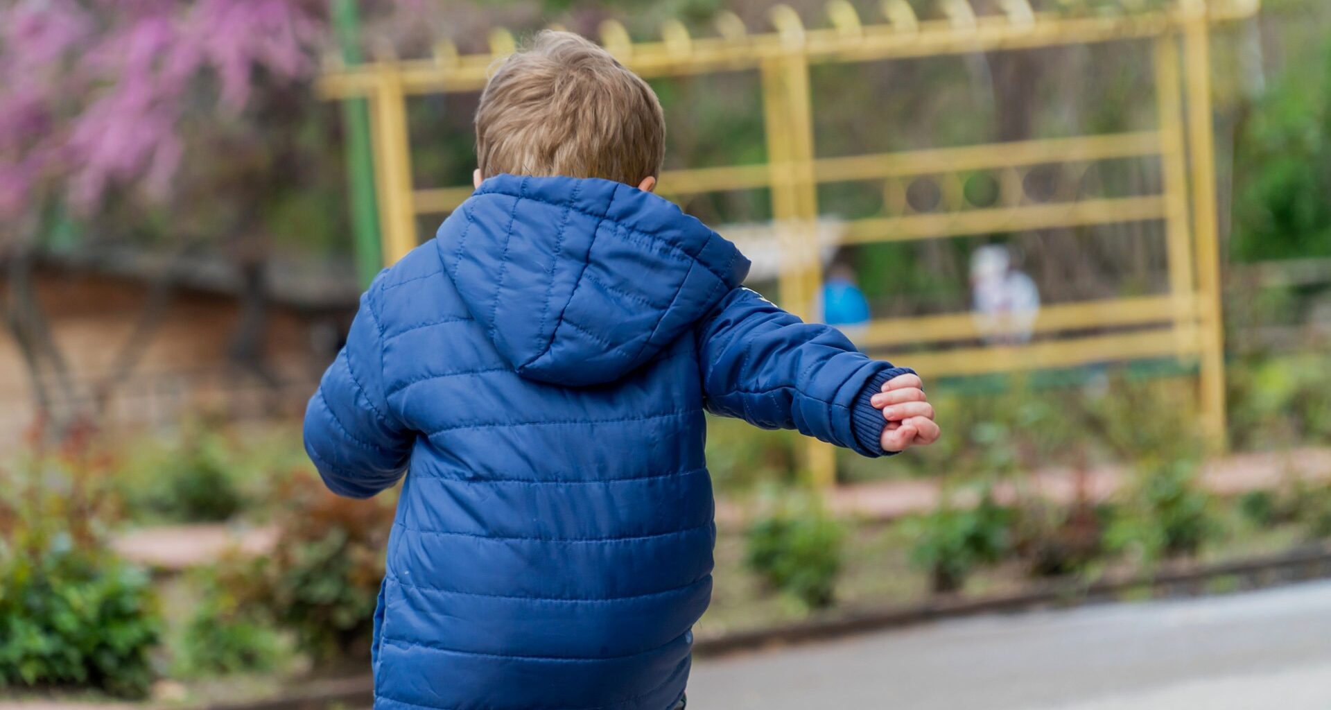Pojke med blå jacka springer i park
