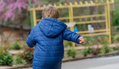Pojke med blå jacka springer i park
