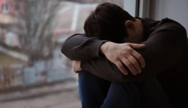 Man sitter intill fönster och gömmer sitt ansikte.