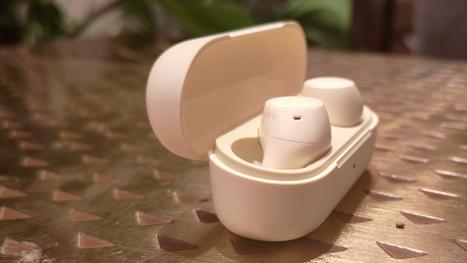 Sony WF-C510 i sitt laddningsfodral p&aring; ett bronsf&auml;rgat bord.