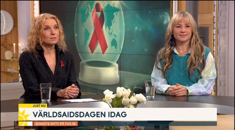 Alexandra Arrhén och Anna Mia Ekström sitter i studion på tv4 Nyhetsmorgon. Bakgrunden är en bild på en illustrerad jordglob med Röda bandet lagt ovanpå. Det står "Världsaidsdagen idag" med versaler i nedre delen av bilden.
