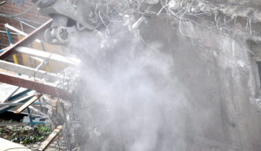 Byggarbetsplats där det rivs och skapar ett moln av stendamm.