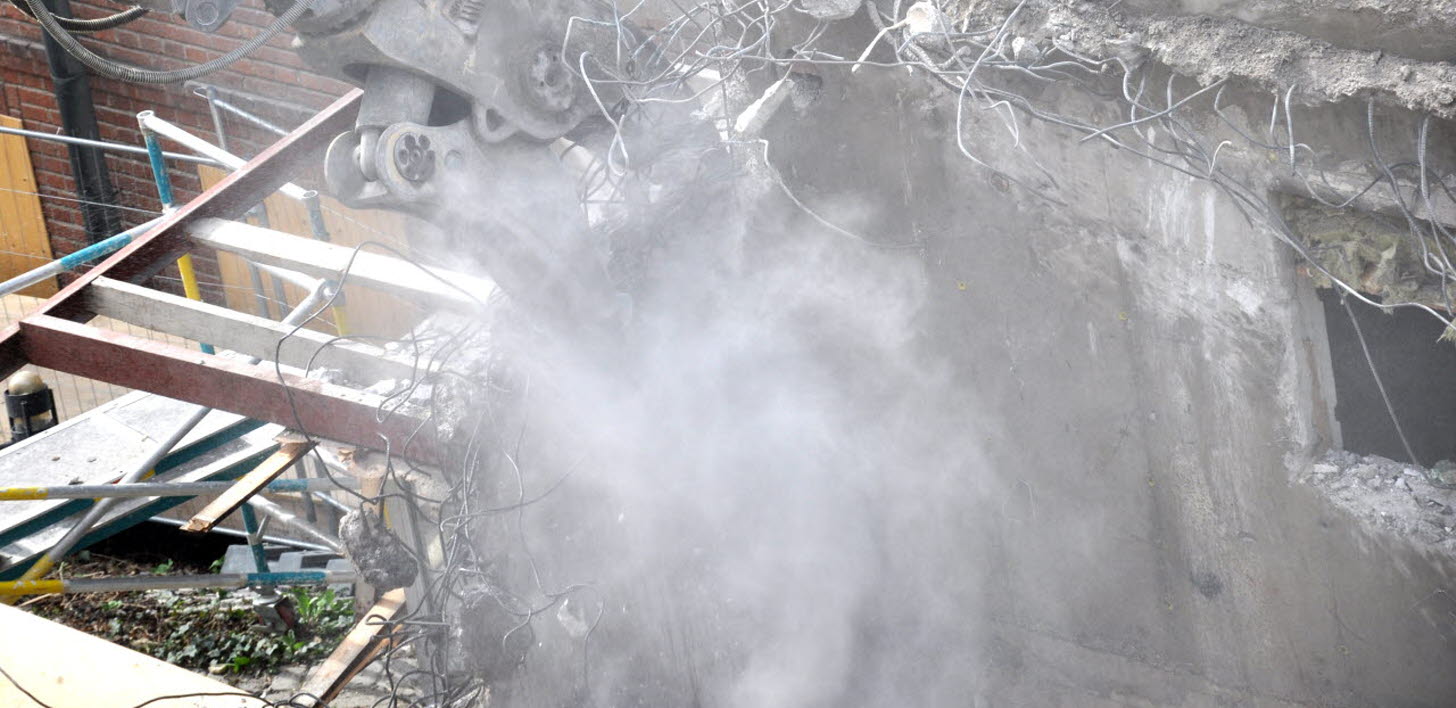 Byggarbetsplats där det rivs och skapar ett moln av stendamm.