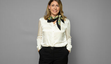 Elisabet Lann ler och tittar in i kameran. Hon bär en vit blus.