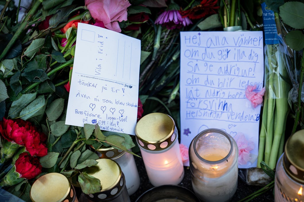 Blommor, handskrivna lappar och tända ljus är samlade i en minnesplats som visar deltagande och minne.