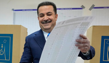 En glad man håller i ett stort papper.